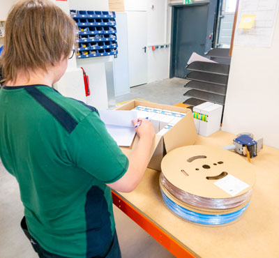 Ein WKK Mitarbeiter im Lager während des Kontrllierens und Einpackens von Kundenbestellungen.