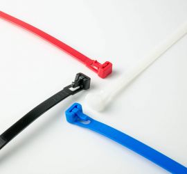 Ein weißer, ein schwarzer, ein roter und ein blauer wiederverwendbarer Kabelbinder auf einem weißen Hintergrund.